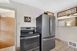 Kitchen featuring stainless steel appliances, light tile patterned floors, and ceiling fan