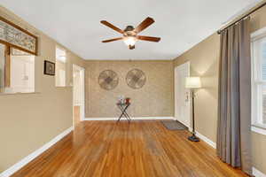 Unfurnished room with a ceiling fan, light wood-type flooring, and an accent wall