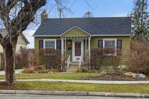 View of front of property featuring roof with shingles, a chimney, and a front yard