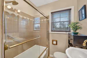 Bathroom with a sink and bath / shower combo with glass door