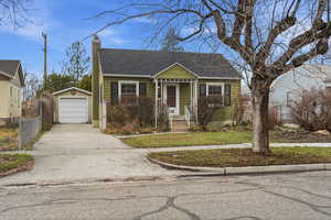 Bungalow with an outbuilding, roof with shingles, a chimney, a detached garage, and concrete driveway