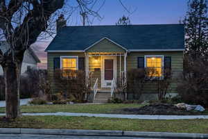 View of front facade featuring a chimney, a front lawn, and roof with shingles