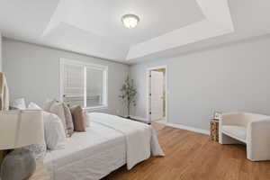 Bedroom featuring light wood-style floors and a tray ceiling