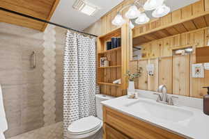 Bathroom with vanity, wooden ceiling, a shower stall, and wood walls