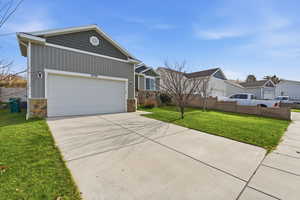 View of front of property with concrete driveway, stone siding, board and batten siding, and a garage