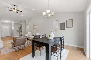 Dining space featuring light wood-type flooring, a ceiling fan, vaulted ceiling, arched walkways, and a chandelier