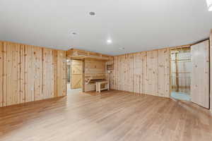 Basement featuring light wood finished floors and wooden walls