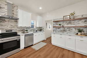 Kitchen featuring open shelves, stainless steel appliances, white cabinets, light wood finished floors, and light stone countertops