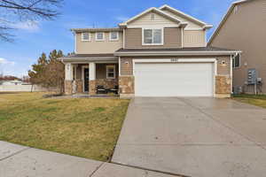 View of front of home with covered porch, stone siding, concrete driveway, and an attached garage