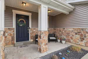 Property entrance featuring stone siding and covered porch