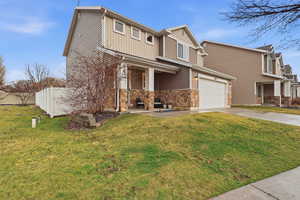 View of front of property featuring driveway, stone siding, board and batten siding, and covered porch