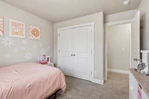 Bedroom with light carpet and a closet