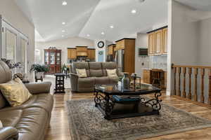 Family room with light wood-style floors, vaulted ceiling, and recessed lighting
