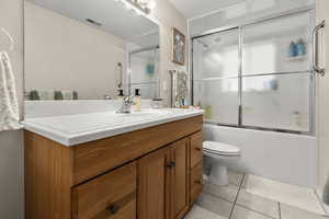 Full bathroom with vanity, combined bath / shower with glass door, and light tile floors