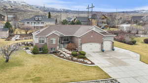 Side view of front of property featuring a front lawn, an attached garage, concrete driveway, brick siding, and a residential view