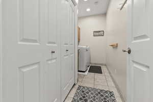 Laundry area featuring light tile floors, washer and clothes dryer, cabinet space, and recessed lighting