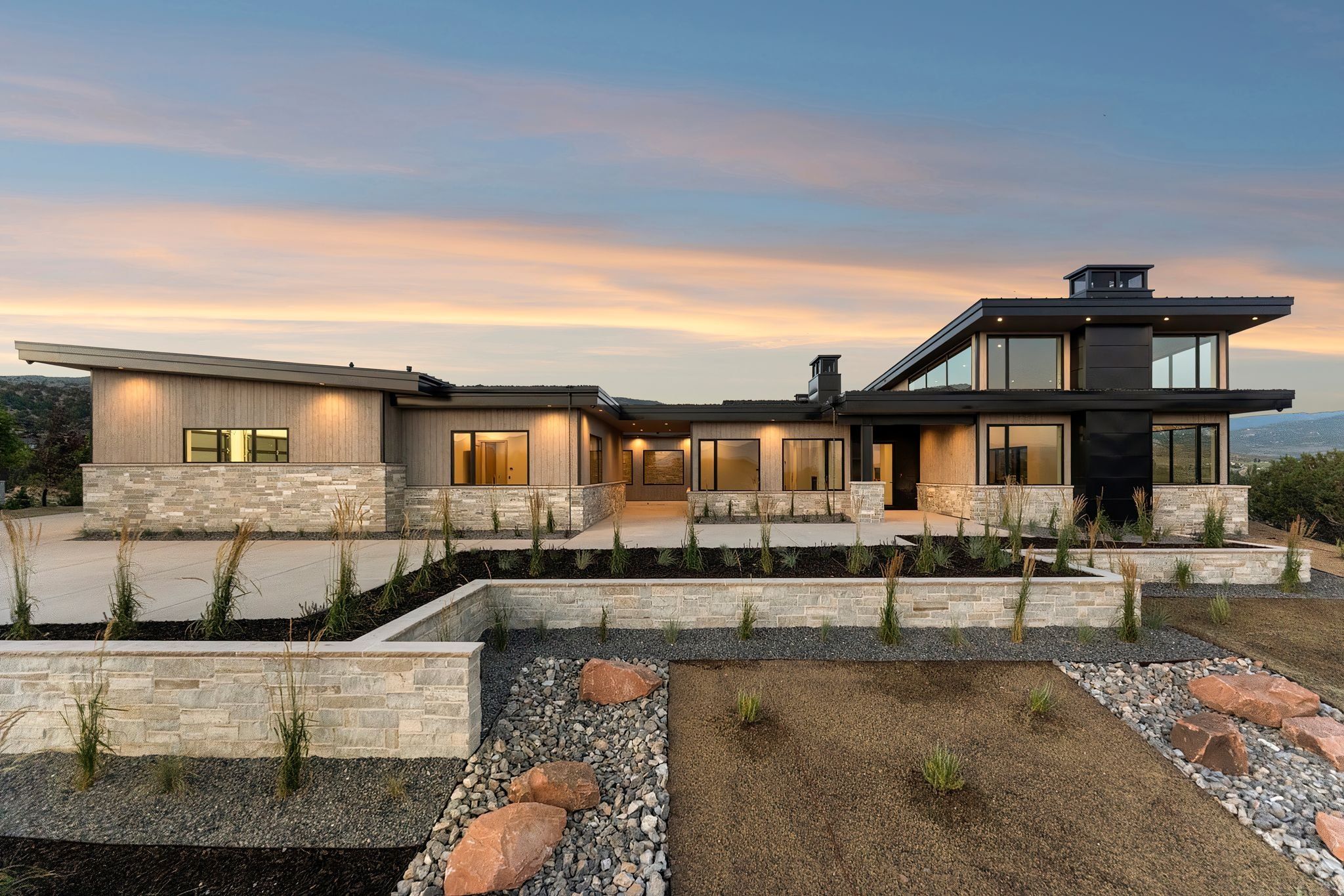 Back of property at dusk with stone siding and a patio area