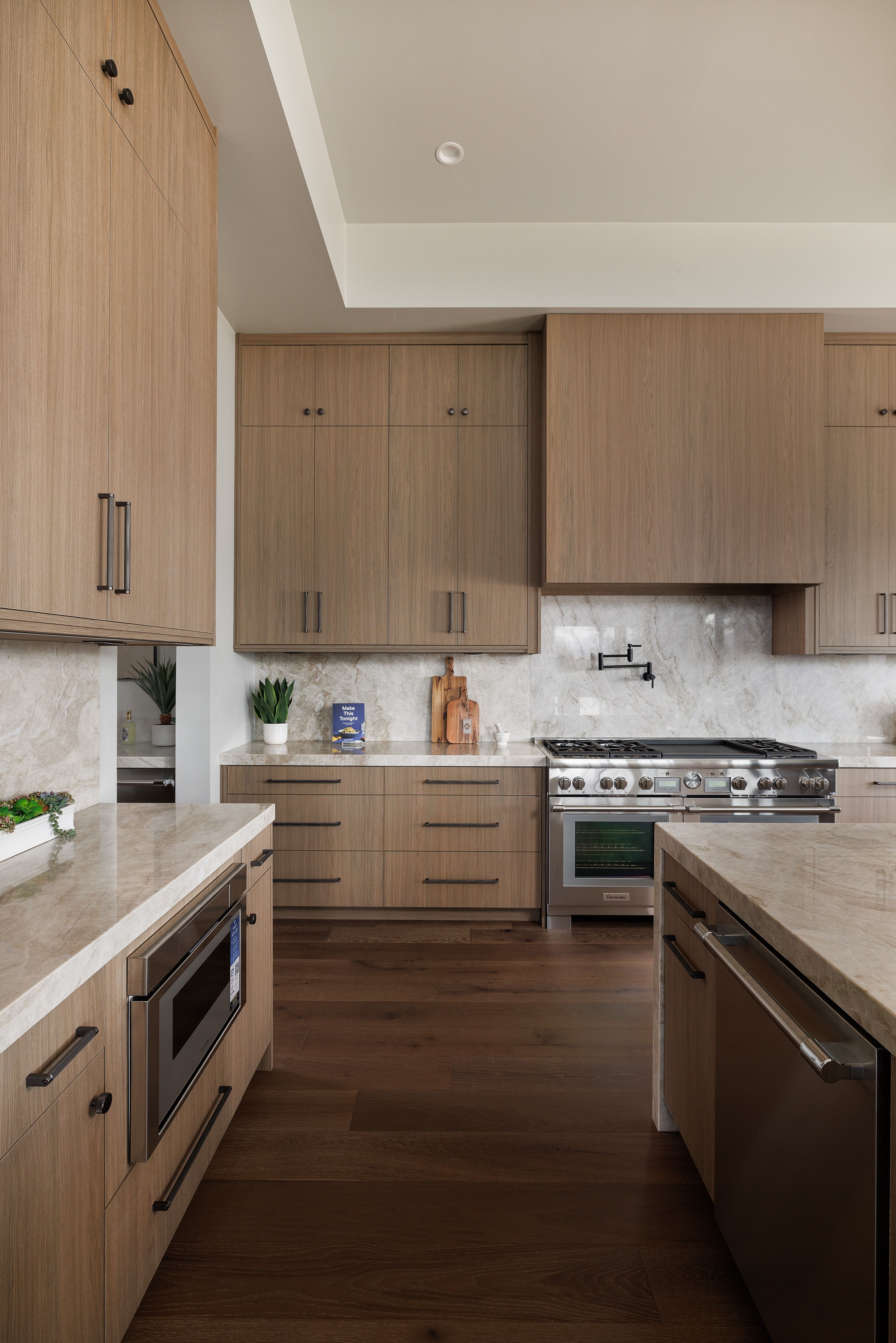 Kitchen featuring light stone countertops, stainless steel appliances, decorative backsplash, and dark wood finished floors