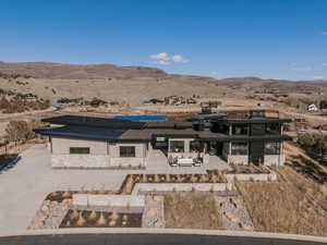 Rear view of property featuring a mountain view, solar panels, a patio area, and a desert view