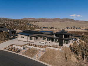 View of front of house with a patio area, a mountain view, solar panels, a chimney, and view of desert