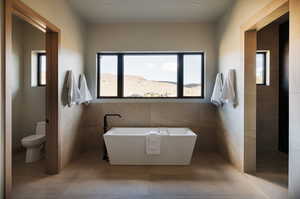 Bathroom featuring a freestanding tub, tile walls, healthy amount of natural light, and walk in shower