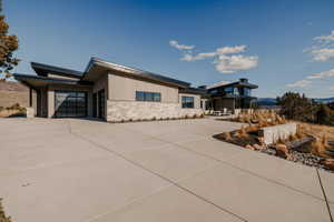 View of front of home with stone siding, driveway, and an attached garage