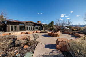 Back of property featuring an outdoor fire pit, board and batten siding, a standing seam roof, a patio, and french doors