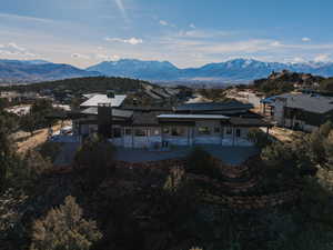 Back of house featuring a patio, a mountain view, and stone siding