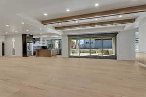 Unfurnished living room with beamed ceiling, light wood-type flooring, and recessed lighting