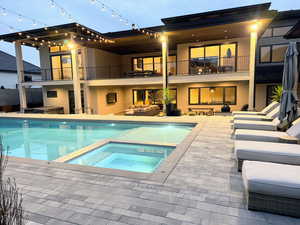 Rear view of house with an outdoor living space, a patio area, stucco siding, and a balcony