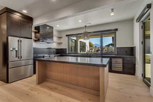 Kitchen with a center island, stainless steel fridge, light wood-style flooring, and wine cooler