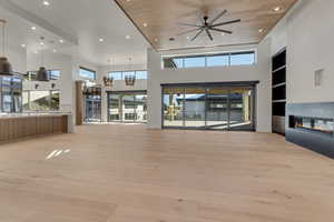Unfurnished living room with built in shelves, recessed lighting, a glass covered fireplace, a high ceiling, and a ceiling fan