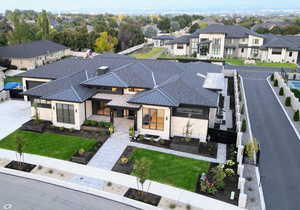 View of front facade featuring a standing seam roof, a residential view, roof with shingles, and stone siding