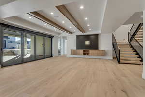 Exercise room with beam ceiling, recessed lighting, and light wood-style floors