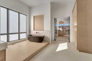 Bathroom with a freestanding tub, a high ceiling, and recessed lighting