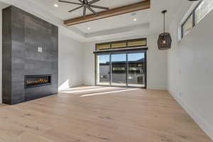 Unfurnished living room with light wood-style flooring, recessed lighting, a tiled fireplace, and a ceiling fan