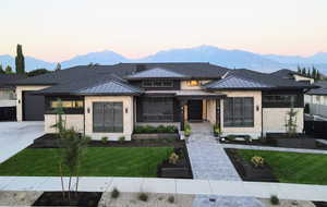 Prairie-style home with a standing seam roof, a front lawn, a mountain view, driveway, and a garage