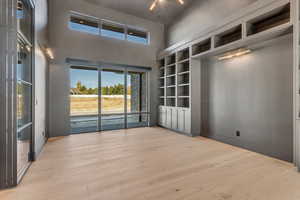 Empty room featuring built in shelves, light wood-style floors, and a high ceiling