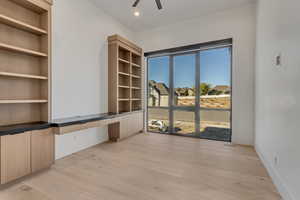 Unfurnished room featuring built in desk, built in features, light wood finished floors, ceiling fan, and recessed lighting