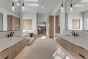 Full bath featuring a skylight, two vanities, and recessed lighting