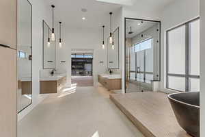 Bathroom with two vanities, a shower stall, a soaking tub, recessed lighting, and a high ceiling