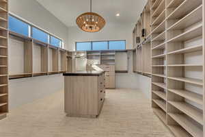 Walk in closet featuring suspended lighting and light carpet