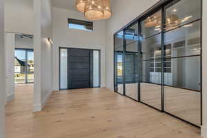 Entryway featuring a high ceiling, light wood-style floors, and hanging lights