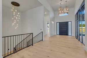 Entryway featuring plenty of natural light, light wood-style floors, hanging lights, and a high ceiling