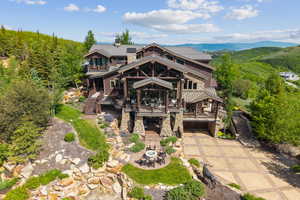 Back of house with concrete driveway, stone siding, a metal roof, an attached garage, and a mountain view
