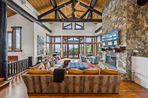 Living room with a fireplace, a high wooden beamed ceiling, and wood-type flooring