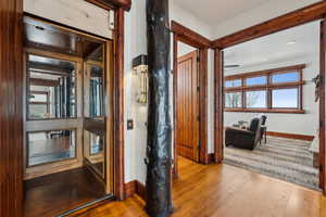 Corridor with wood finished floors, recessed lighting, and elevator