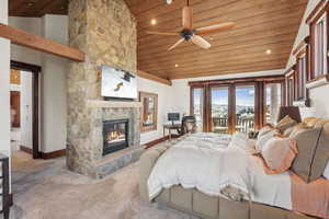 Bedroom featuring access to exterior, a vaulted wood ceiling, a stone fireplace, carpet, and recessed lighting
