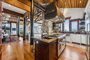 Dual tone kitchen with high end appliances, extractor fan, dark stone countertops, open shelves, and recessed lighting