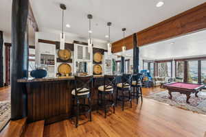 Kitchen featuring billiards, pendant lighting, light wood-style floors, and a kitchen bar